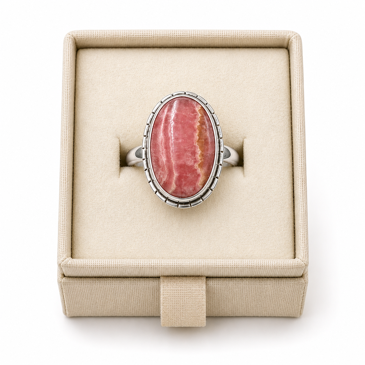 Sterling silver bezel-set ring with an oval rhodochrosite cabochon displayed in a soft linen jewelry box on a white background -Clover's Charm.