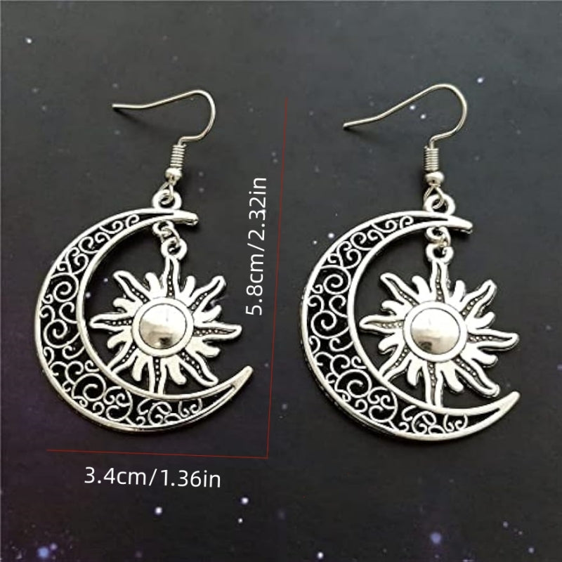 Silver crescent moon earrings with sun charm shown on dark background for size reference