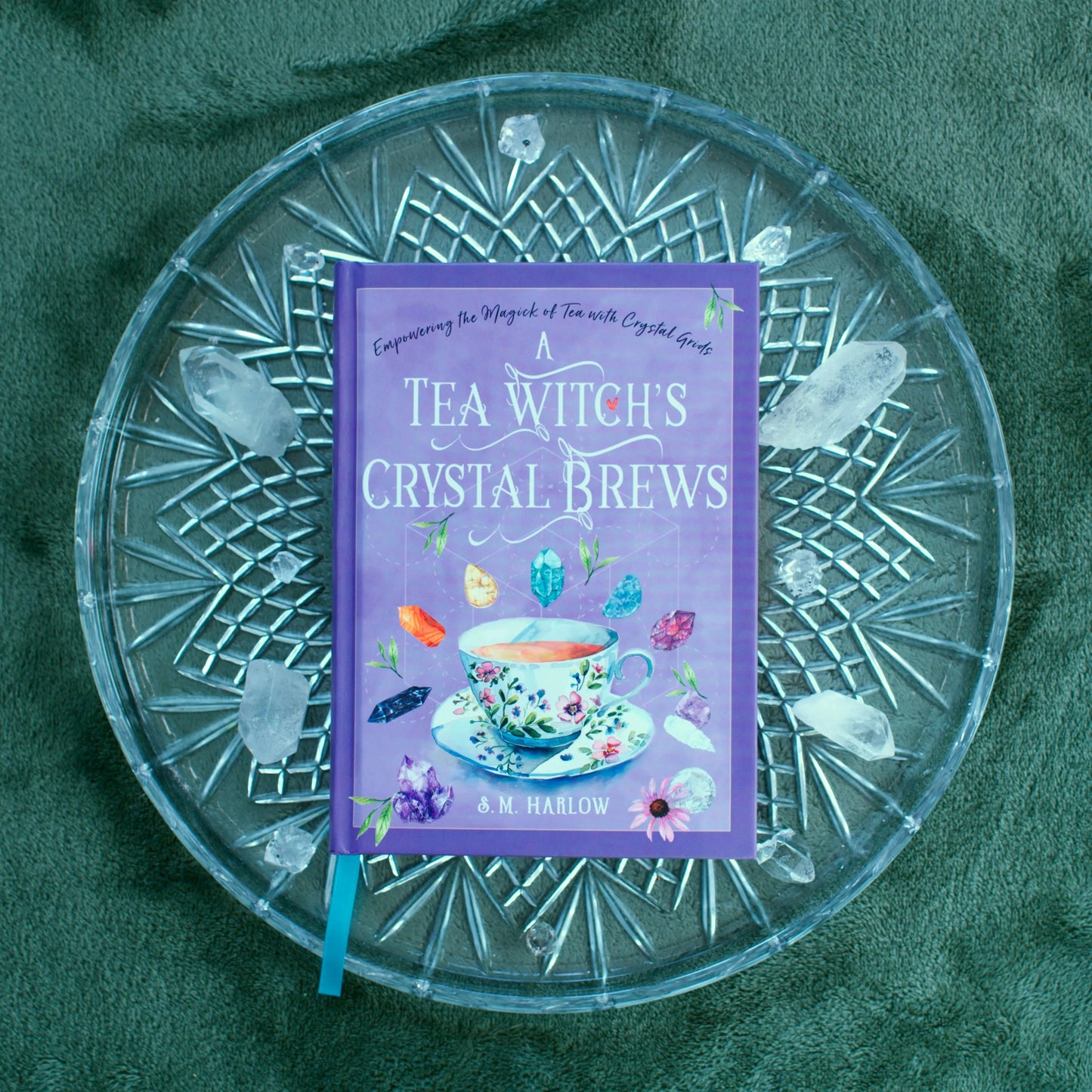 Book titled 'A Tea Witch's Crystal Brews' on a decorative glass plate with a green background