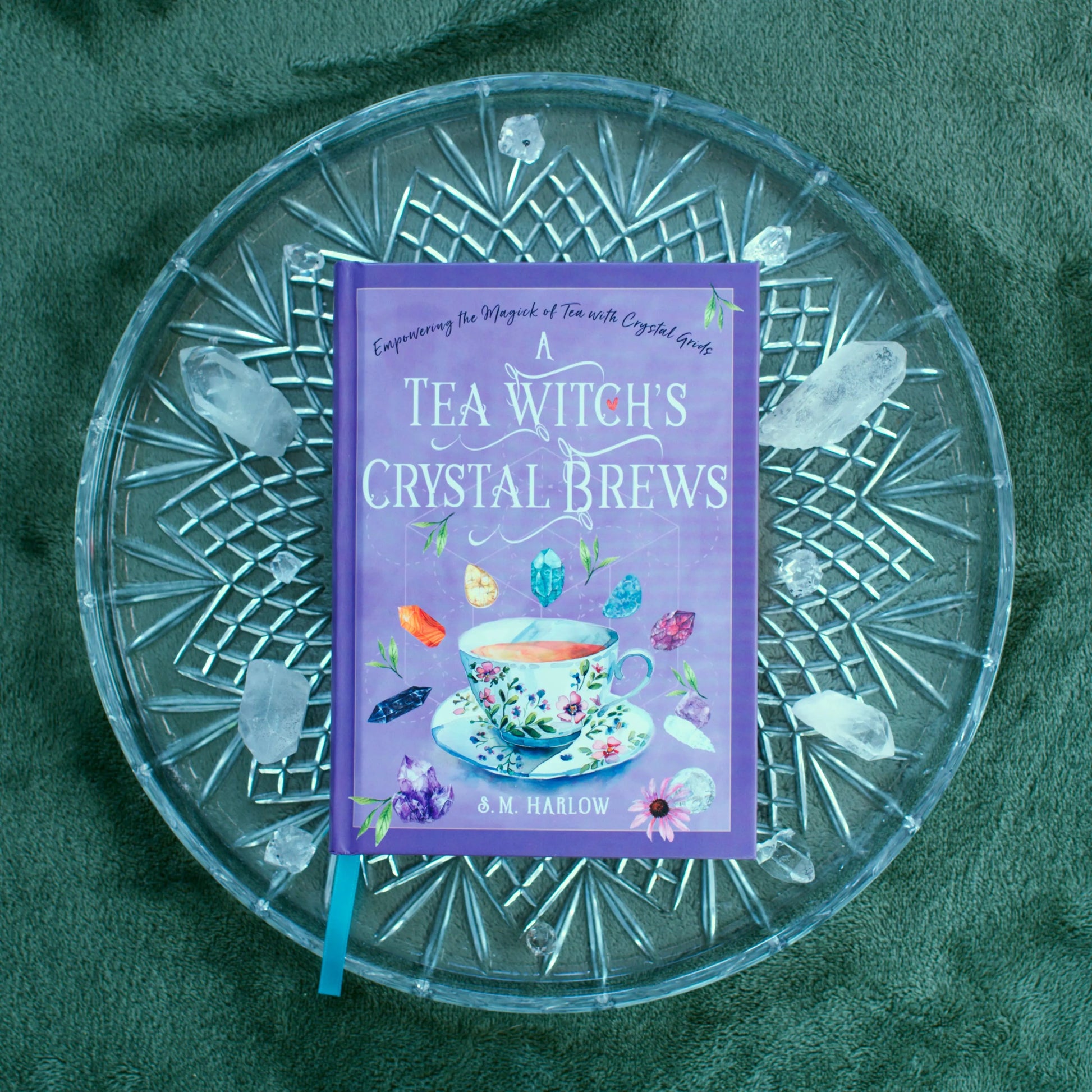Book titled 'A Tea Witch's Crystal Brews' on a decorative glass plate with a green background