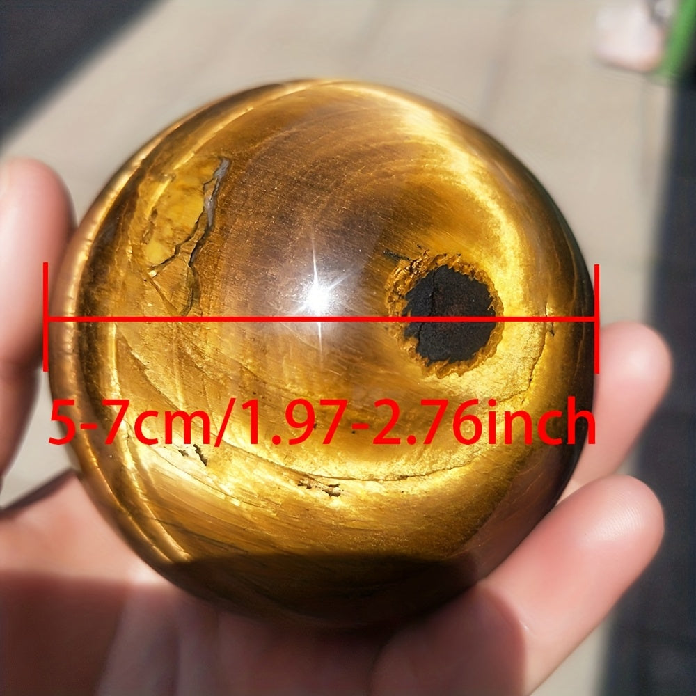 Tiger's eye sphere held in a hand with measurement text overlay