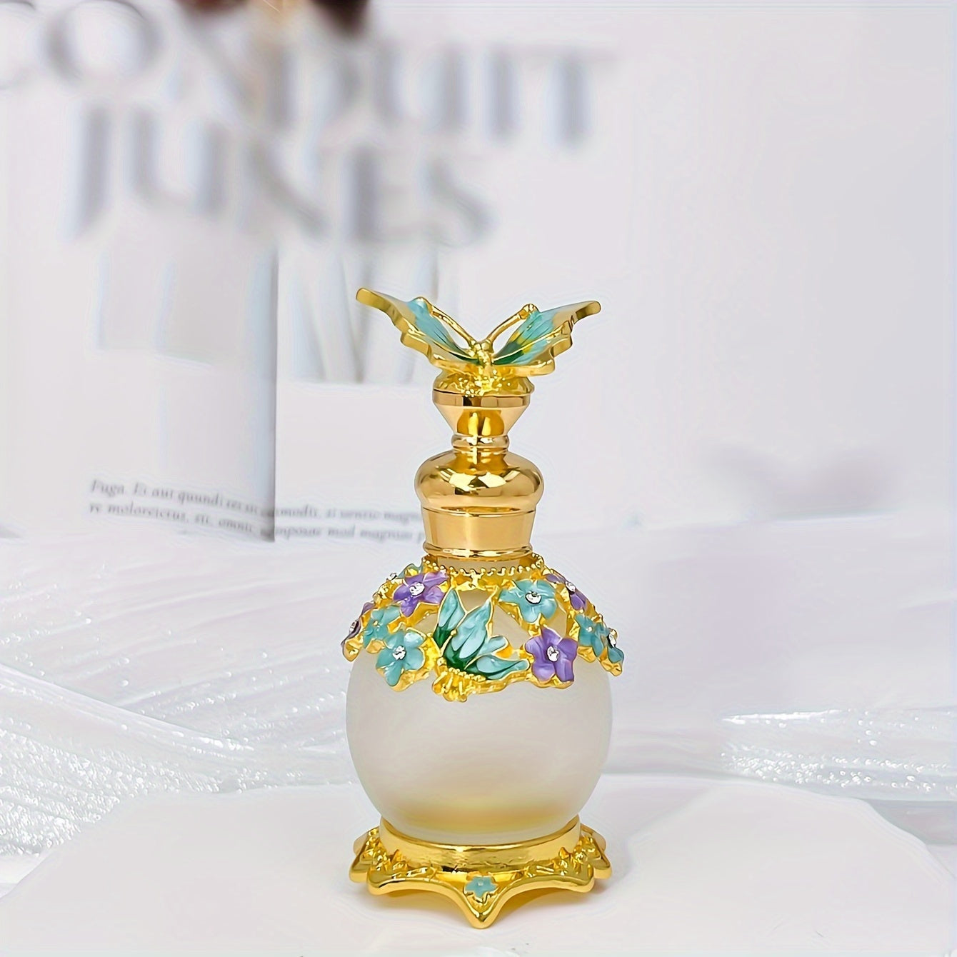 Vintage style glass perfume bottle with butterfly stopper on white surface.
