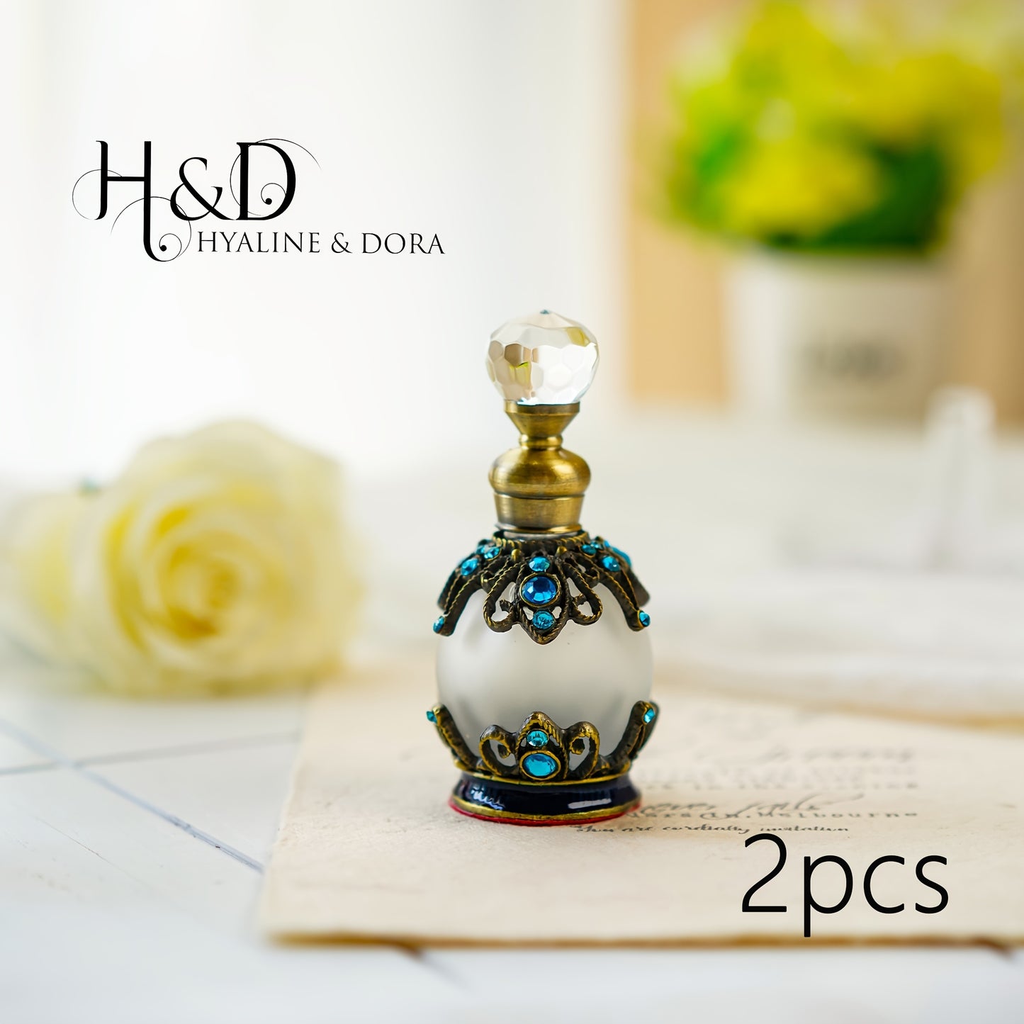 H&D HYALINE & DORA 2pcs 15ml Crystal Decorative Perfume Bottle, Vintage style Rhinestone Jeweled Glass Perfume Bottle, Refillable Perfume Bottles sitting on a letter with yellow roses blurred in the background on a white surface.

