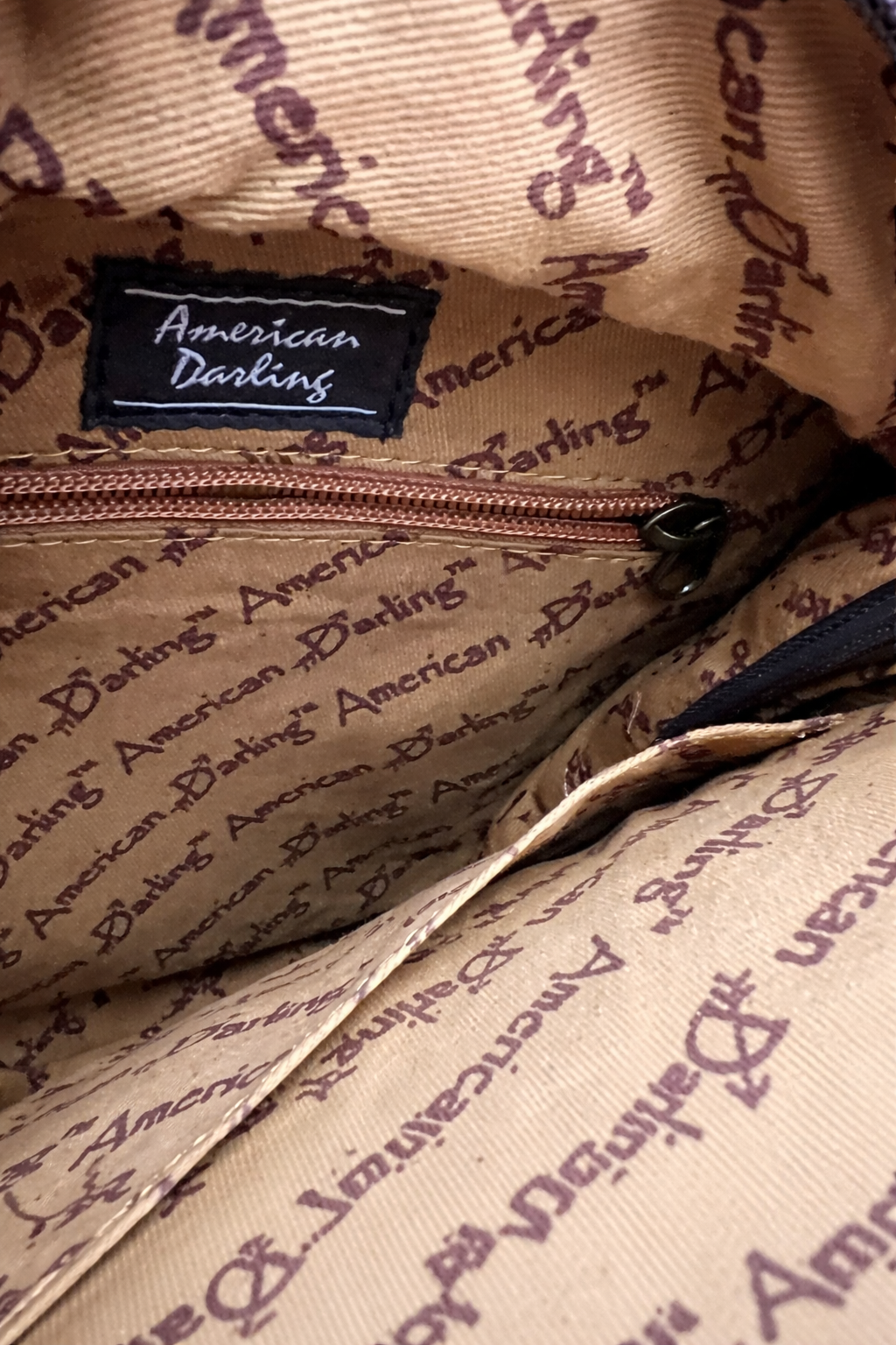 Close-up of a beige bag with 'American Darling' branding.