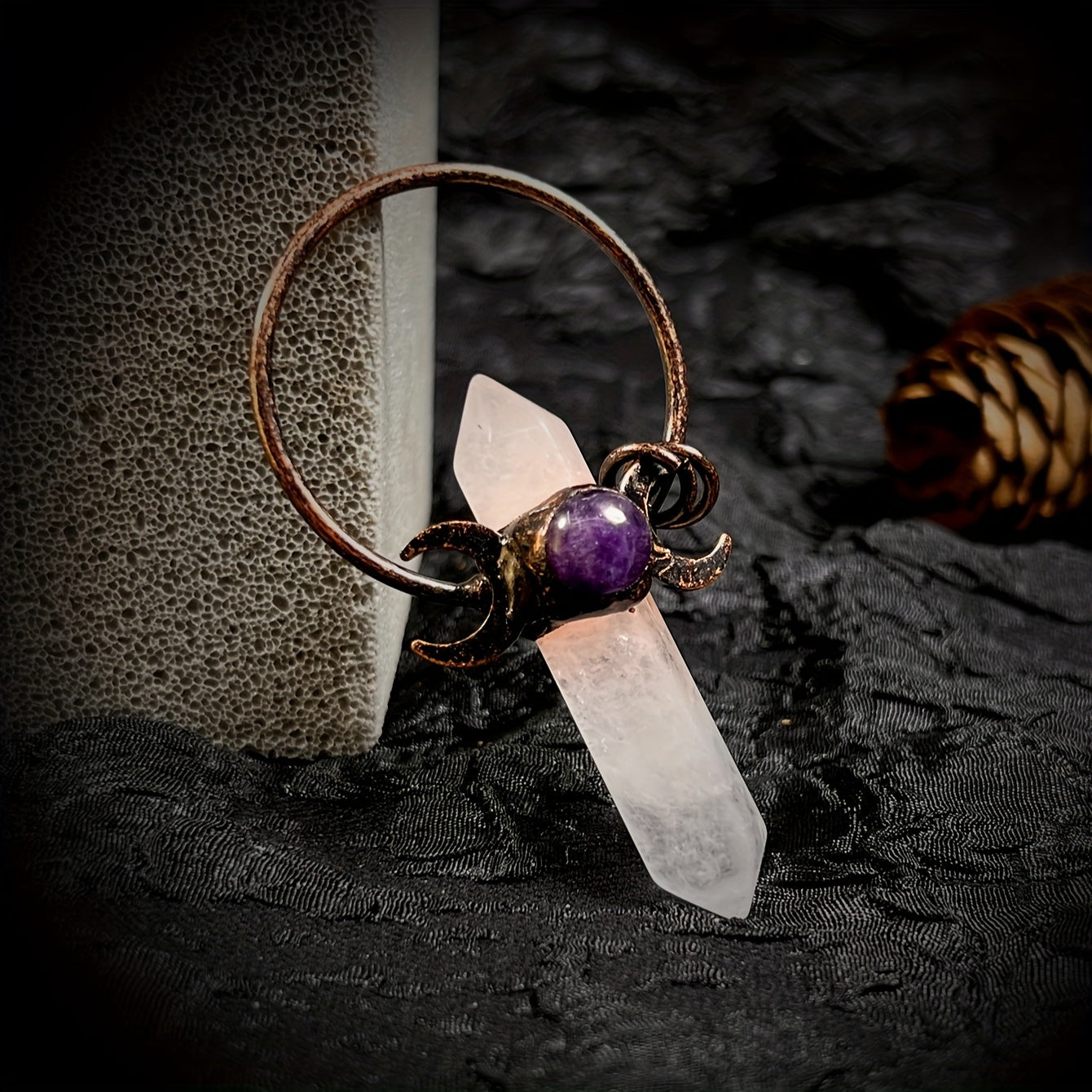 Decorative ring with a crystal and purple gemstone on a textured surface