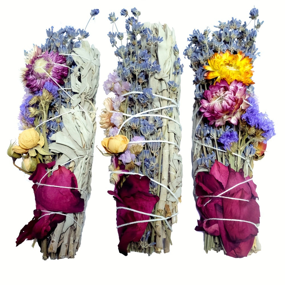 Three bundles of dried flowers and herbs tied together with pink cloth on a white background