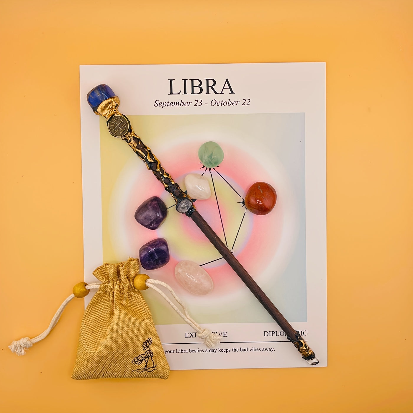 Decorative item with crystals and a small bag on a Libra zodiac card with a yellow background