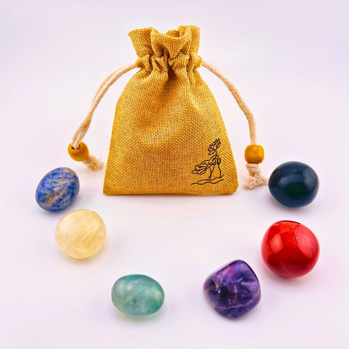 Set of colorful stones with a yellow drawstring bag on a white background