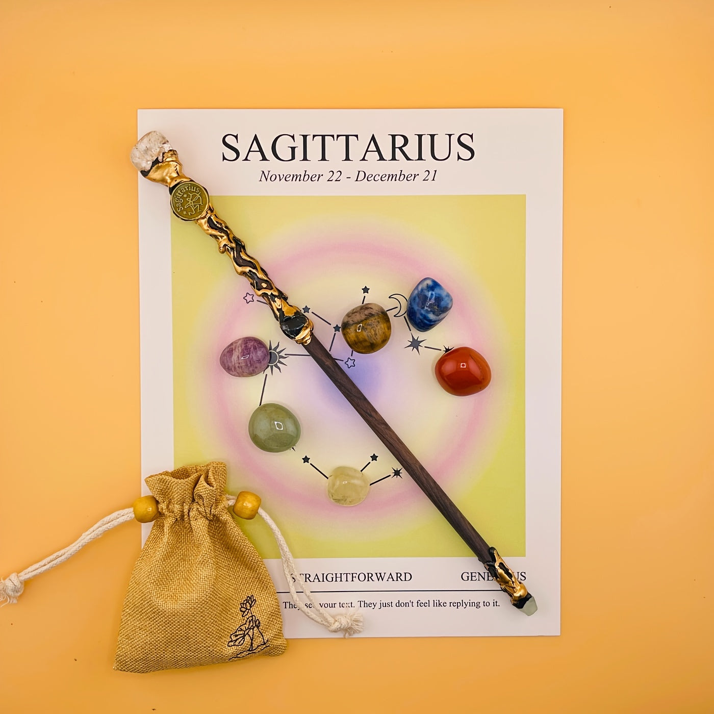 Decorative wand with colorful beads on a Sagittarius zodiac card on an orange background