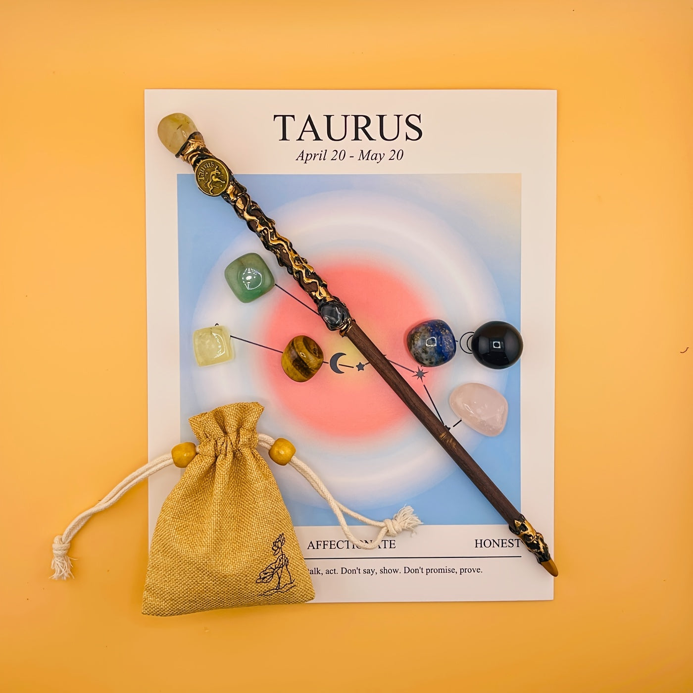 Decorative wand with gemstones on a Taurus horoscope card against an orange background