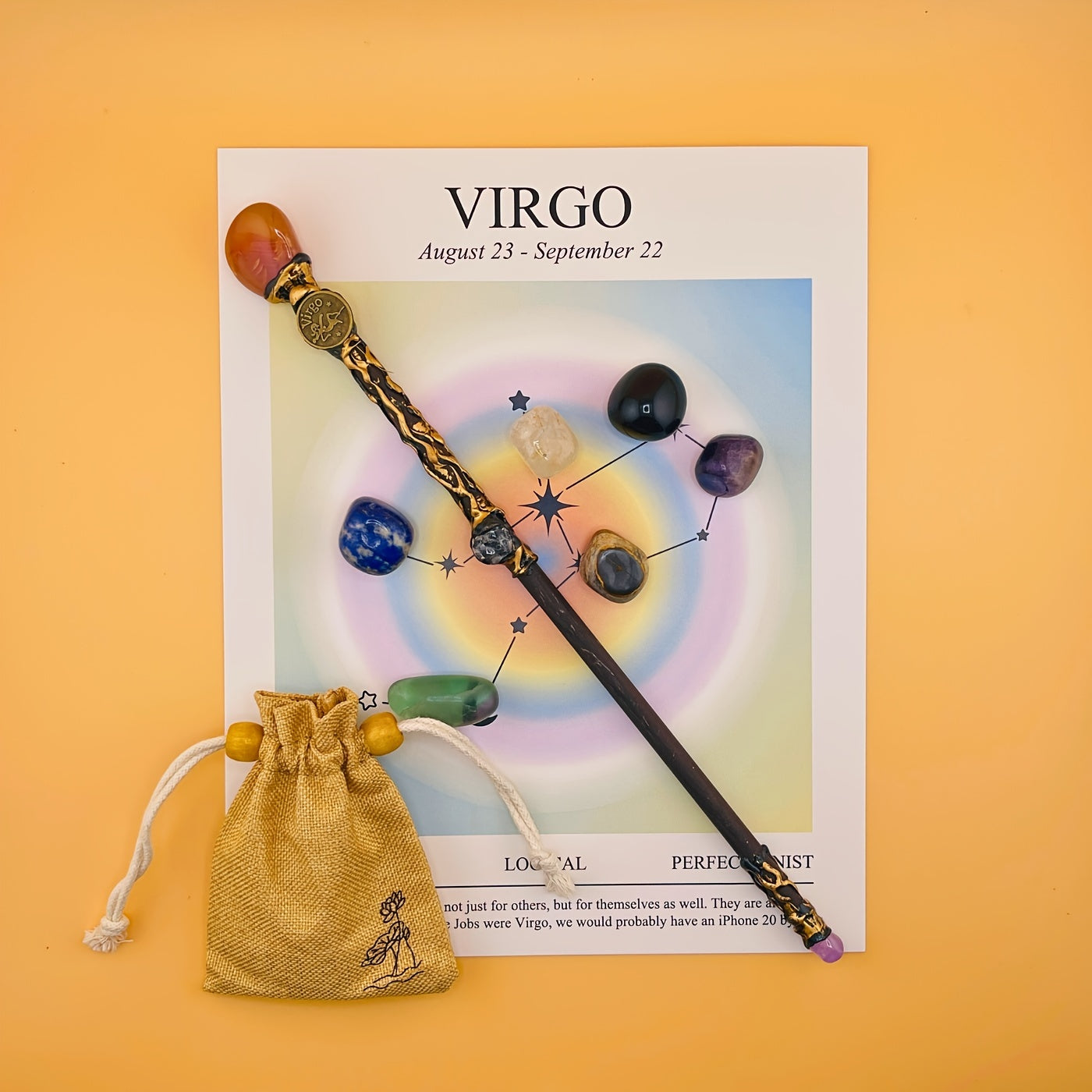 Decorative wand with gemstones on a Virgo zodiac card against an orange background